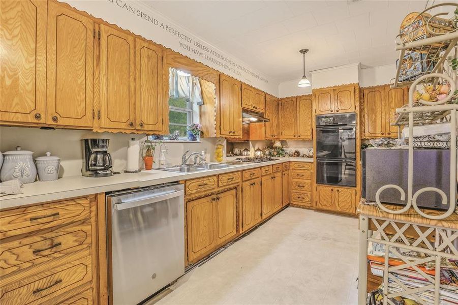 Kitchen featuring wood cabinetry, white countertops, a stainless steel dishwasher, and a built-in double oven Kitchen featuring wood cabinetry, white countertops, a stainless steel dishwasher, and a built-in double oven