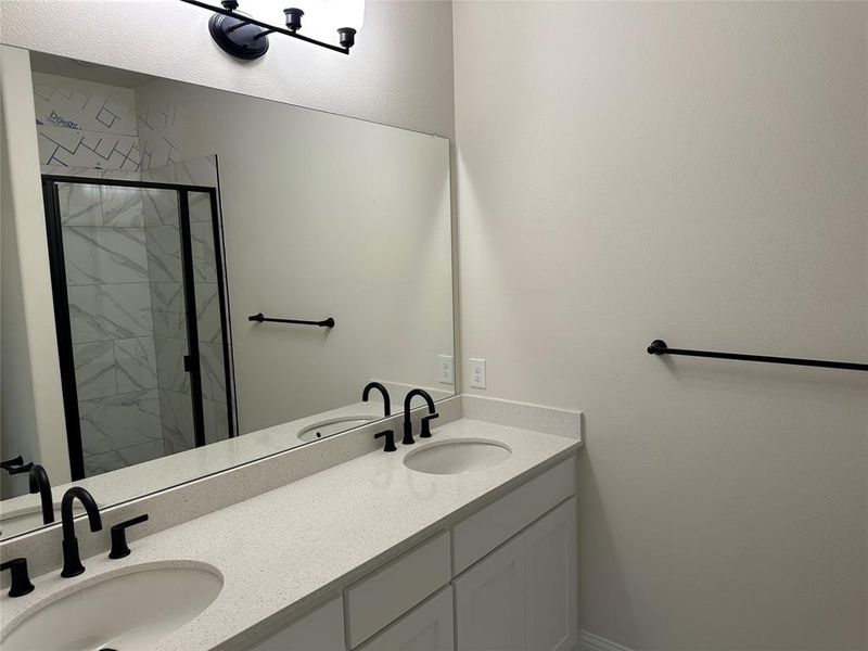 Primary Bathroom featuring double vanity, a shower stall, and a sink