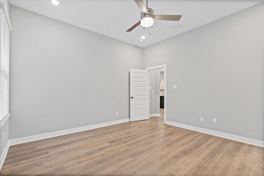 Spacious room featuring vaulted ceilings, recessed lighting, wood-finish flooring, and a modern ceiling fan Spacious room featuring vaulted ceilings, recessed lighting, wood-finish flooring, and a modern ceiling fan