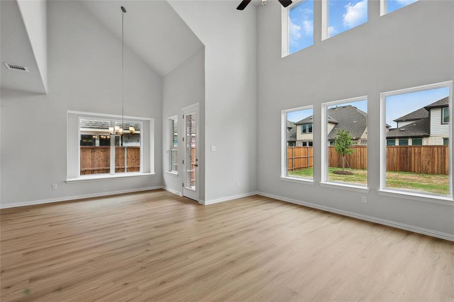 Unfurnished living room with a chandelier, light wood-type flooring, a ceiling fan, and vaulted ceiling