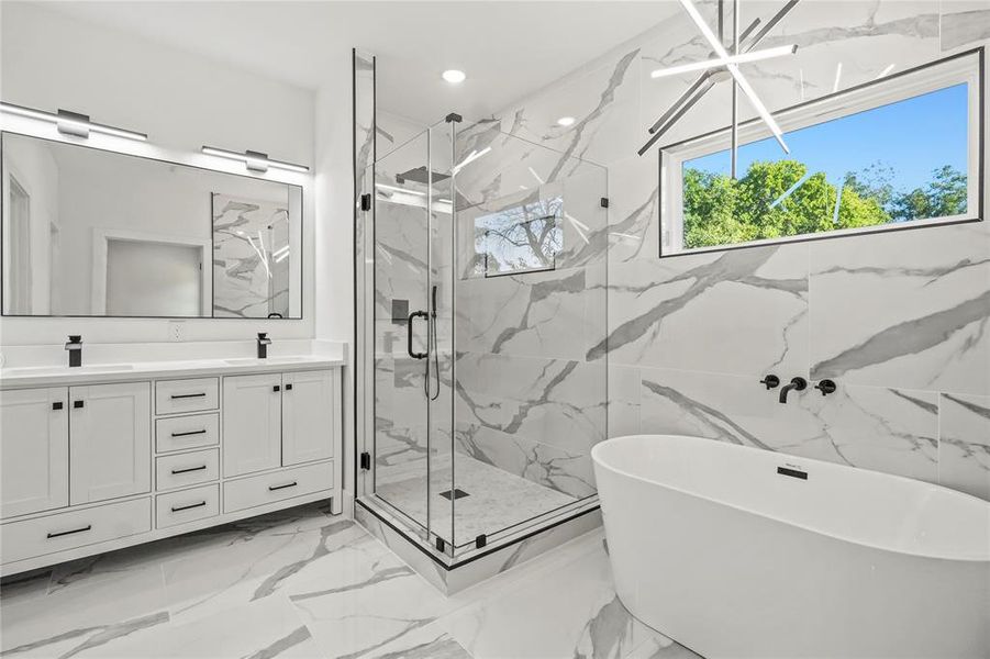 Full bathroom featuring a freestanding bath, light marble finish floors, double vanity, a marble finish shower, and recessed lighting