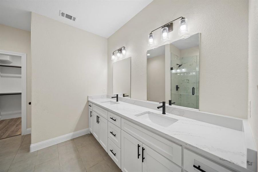 Bathroom with tile patterned floors, dual bowl vanity, and walk in shower