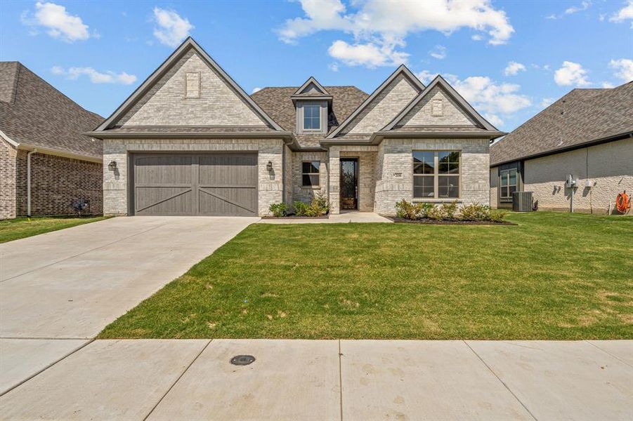 View of front of house featuring central AC unit, a front yard, and a garage