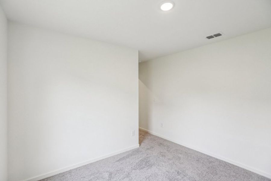 A room with a carpet and a light on the wall.