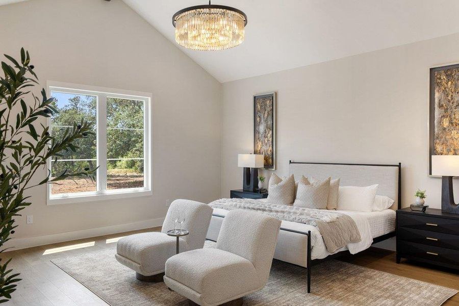Natural light floods this primary bedroom featuring vaulted ceilings and polished hardwood flooring.