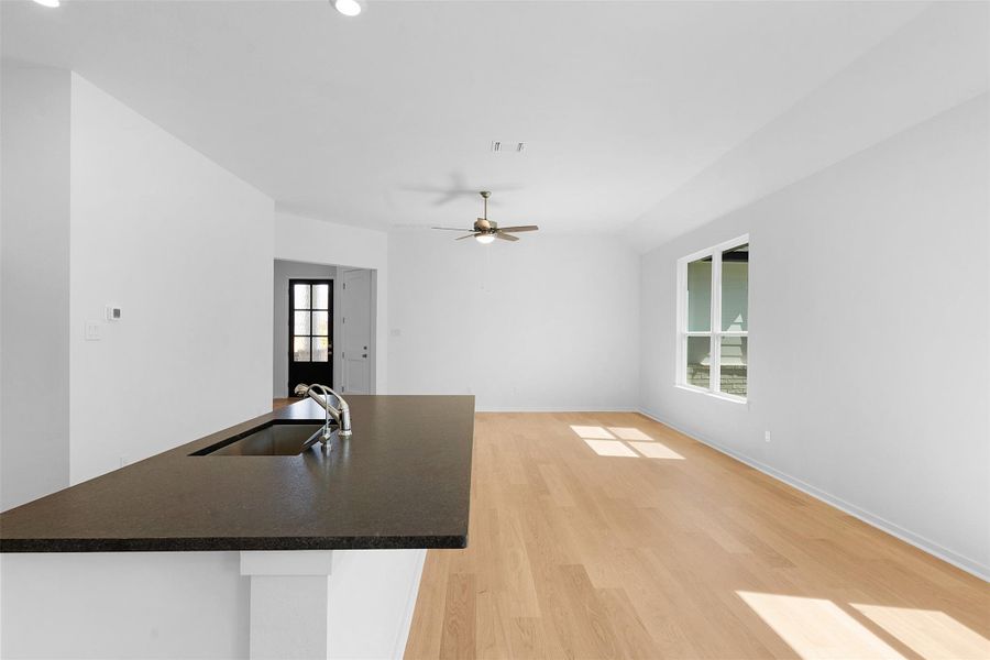Kitchen with light wood-style flooring, an island with sink, a ceiling fan, and open floor plan Kitchen with light wood-style flooring, an island with sink, a ceiling fan, and open floor plan