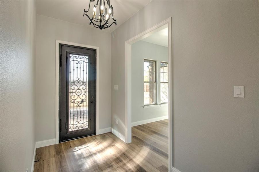 Foyer entrance featuring light hardwood / wood-style floors and an inviting chandelier