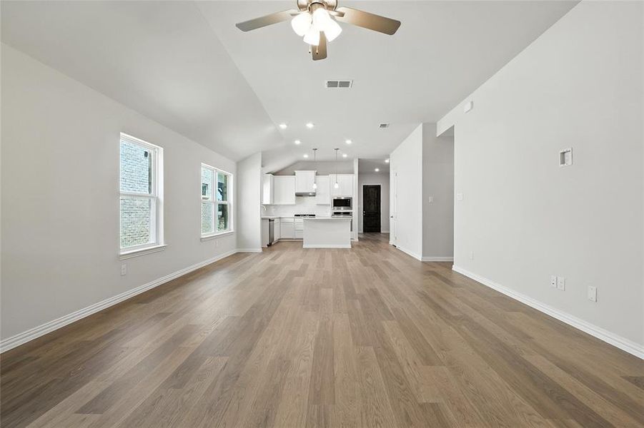 Unfurnished living room featuring vaulted ceiling, ceiling fan, light wood-style floors, and recessed lighting Unfurnished living room featuring vaulted ceiling, ceiling fan, light wood-style floors, and recessed lighting