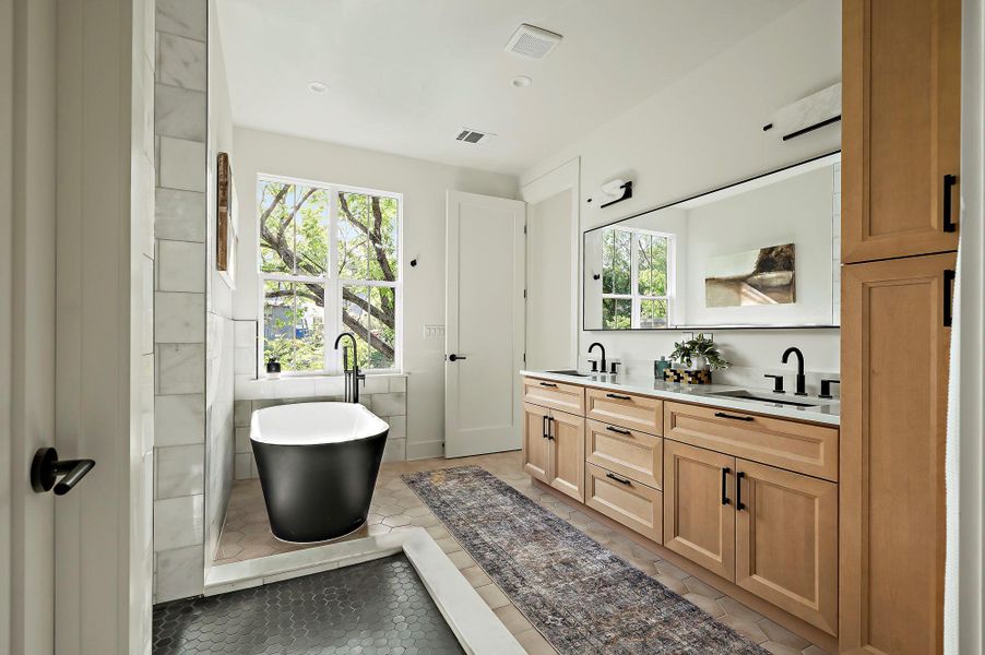 Bathroom featuring plenty of natural light, a freestanding bath, and double vanity