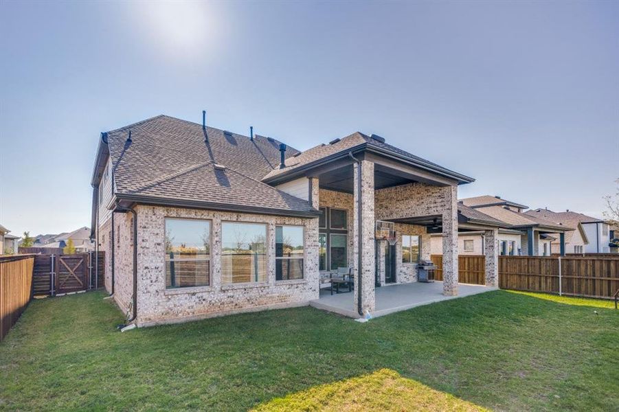 Back of house with a fenced backyard, a patio area, brick siding, and a gate