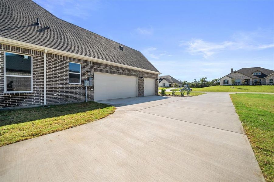View of property exterior featuring brick siding, roof with shingles, concrete driveway, and a lawn View of property exterior featuring brick siding, roof with shingles, concrete driveway, and a lawn