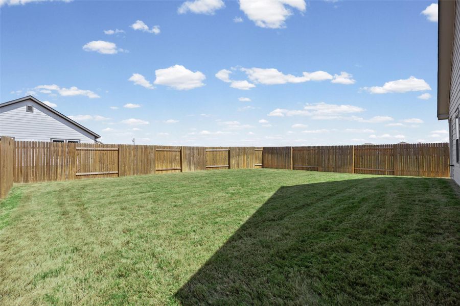 An expansive green lawn is fully enclosed by a sturdy wooden privacy fence. An expansive green lawn is fully enclosed by a sturdy wooden privacy fence.