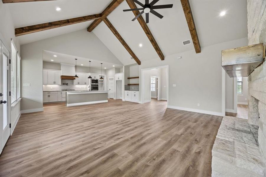 Unfurnished living room featuring high vaulted ceiling, light wood-type flooring, recessed lighting, ceiling fan, and a fireplace Unfurnished living room featuring high vaulted ceiling, light wood-type flooring, recessed lighting, ceiling fan, and a fireplace