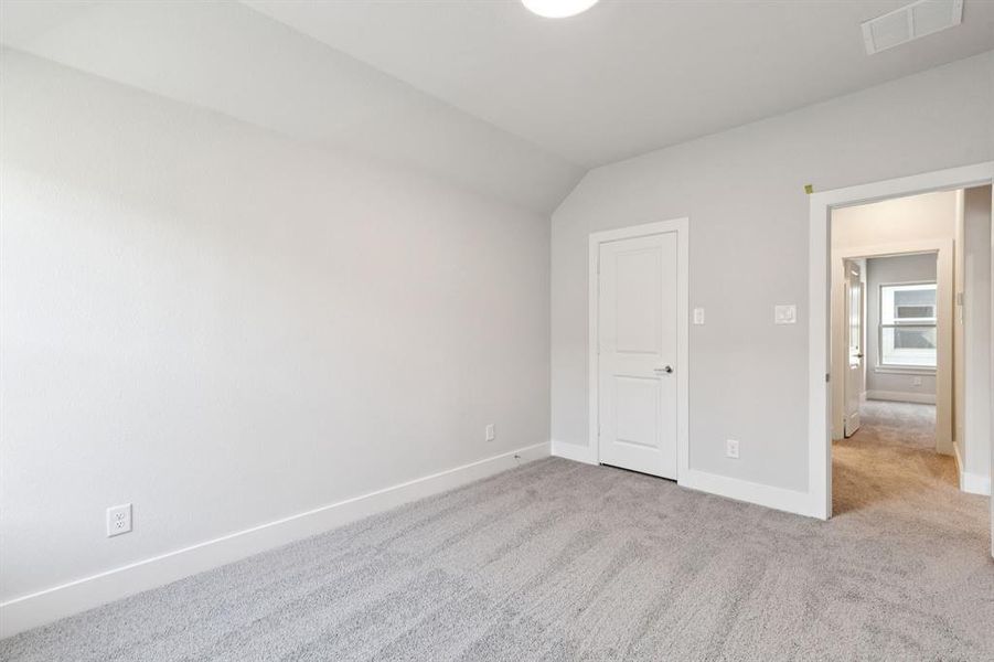 Unfurnished bedroom featuring carpet flooring and lofted ceiling Unfurnished bedroom featuring carpet flooring and lofted ceiling