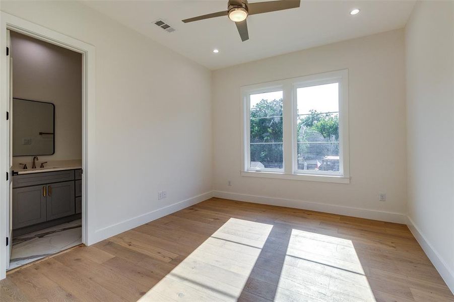 Unfurnished bedroom with connected bathroom, sink, ceiling fan, and light hardwood / wood-style floors