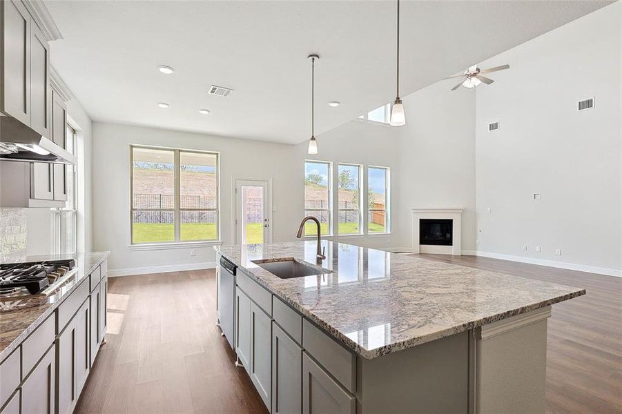 Kitchen with ceiling fan, hardwood / wood-style floors, sink, a center island with sink, and gray cabinetry