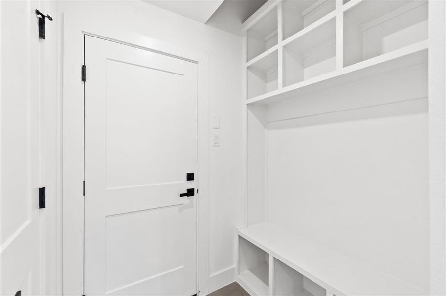 Mudroom with custom built in cabinetry separating the kitchen and garage.