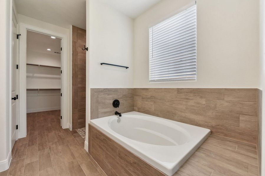 Full bathroom with a garden tub, a spacious closet, and a shower