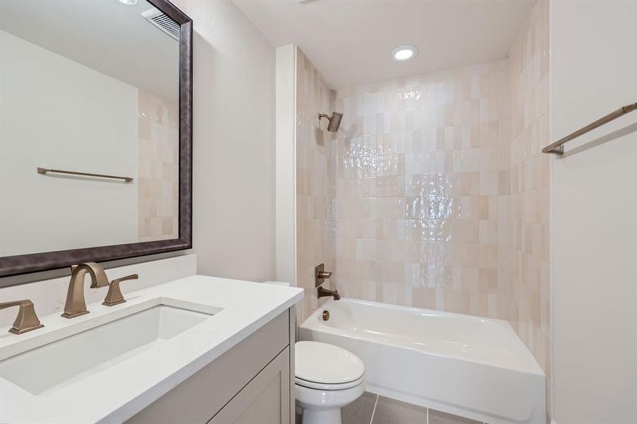 Full bathroom featuring tiled shower / bath, vanity, toilet, and tile patterned flooring