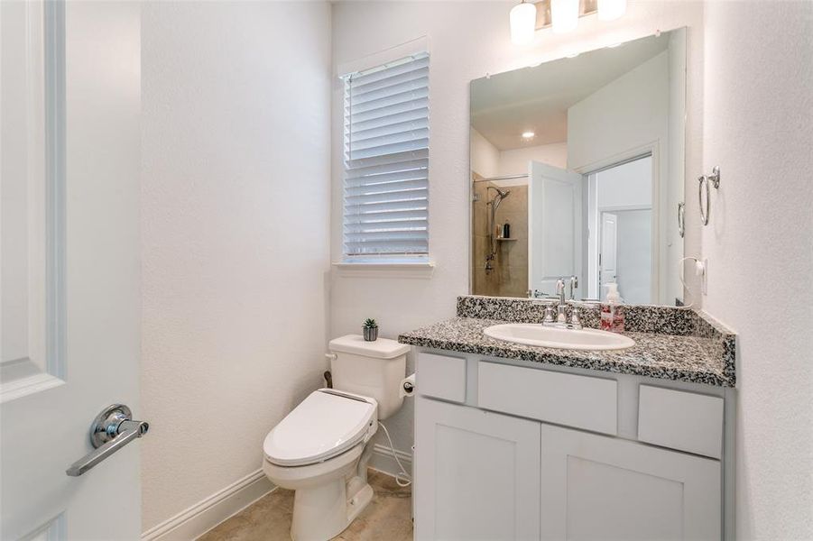 Bathroom with vanity, a tile shower, and a textured wall
