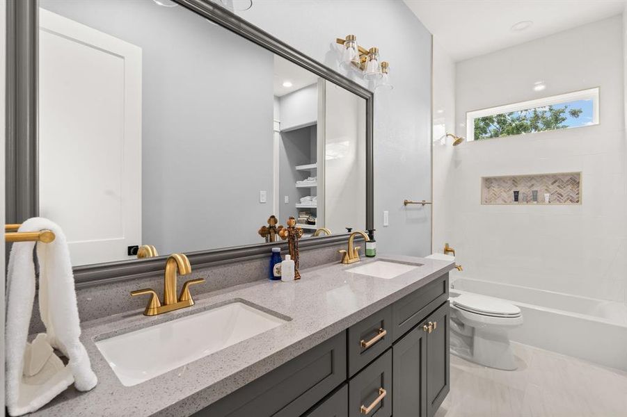 The bathroom includes a double sink vanity, a tiled shower/tub combo, and a toilet, providing a practical and stylish space for daily use.