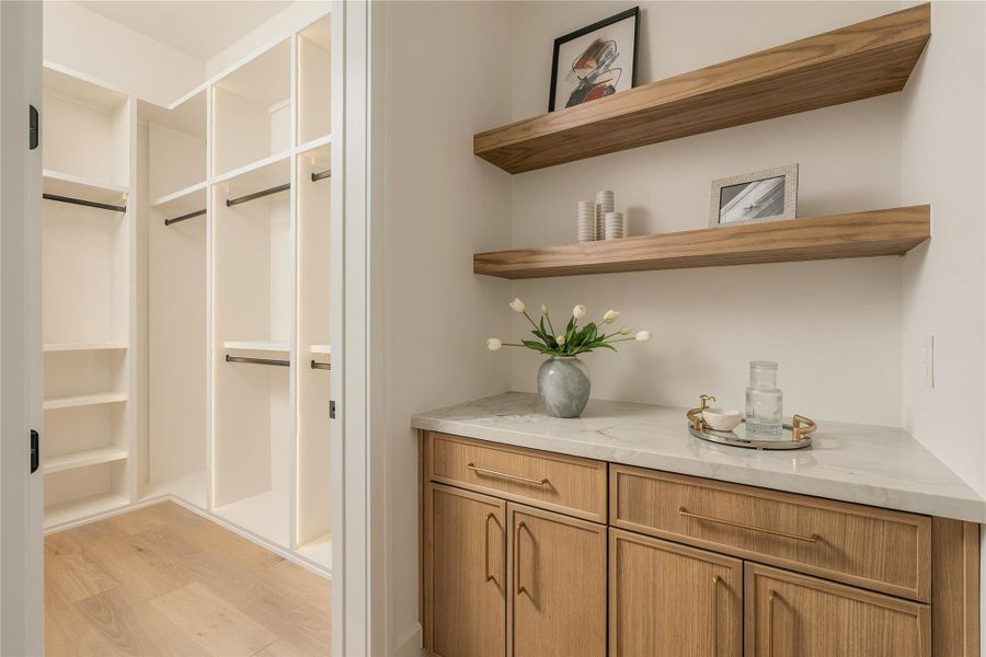 One of two closets in the primary bedroom with dedicated coffee bar within the primary suite adds a hotel-inspired touch, complete with custom cabinetry and open shelving for a refined morning ritual.