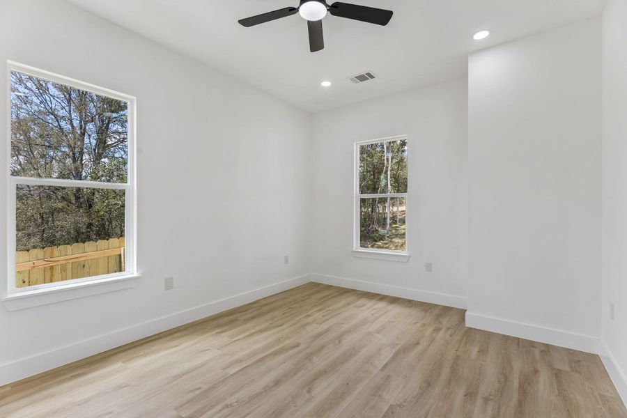 Crisp white walls and light-toned wood flooring define this versatile, window-lit room.