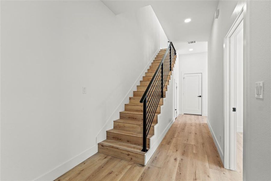 Stairway featuring wood finished floors and recessed lighting