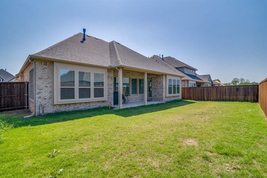 Rear view of property featuring a patio area, a fenced backyard, brick siding, and a yard Rear view of property featuring a patio area, a fenced backyard, brick siding, and a yard