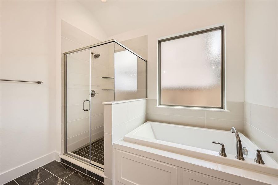 Bathroom featuring a stall shower, marble finish flooring, a bath, and baseboards