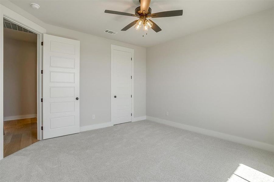 Unfurnished bedroom featuring carpet flooring, visible vents, baseboards, and ceiling fan Unfurnished bedroom featuring carpet flooring, visible vents, baseboards, and ceiling fan