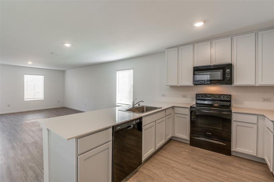Kitchen featuring white cabinetry, kitchen peninsula, sink, and black appliances