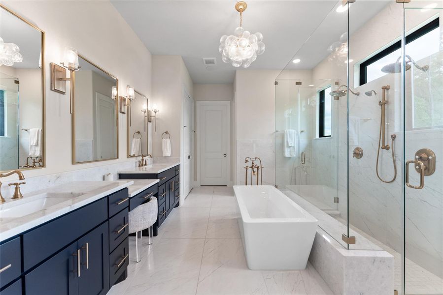 The primary bath delivers a spa inspired experience with dual vanities, navy cabinetry, Shadow Storm marble, and designer mirrors. The layout offers a strong sense of daily luxury with excellent storage and lighting.