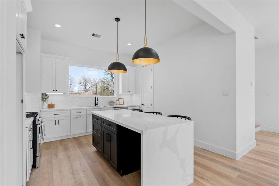 Another angle unveils the breathtaking details of this kitchen, from the exquisite matte finish pulls and knobs to the thoughtful inclusion of a dedicated section for a wine cooler beneath the expansive kitchen island, showcasing both style and practicality.