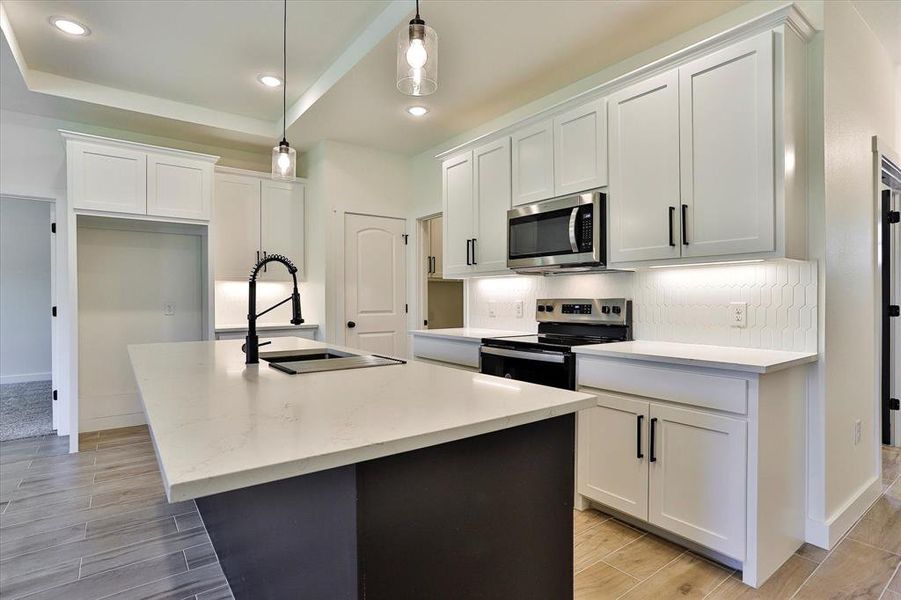 Kitchen featuring pendant lighting, an island with sink, and stainless steel appliances