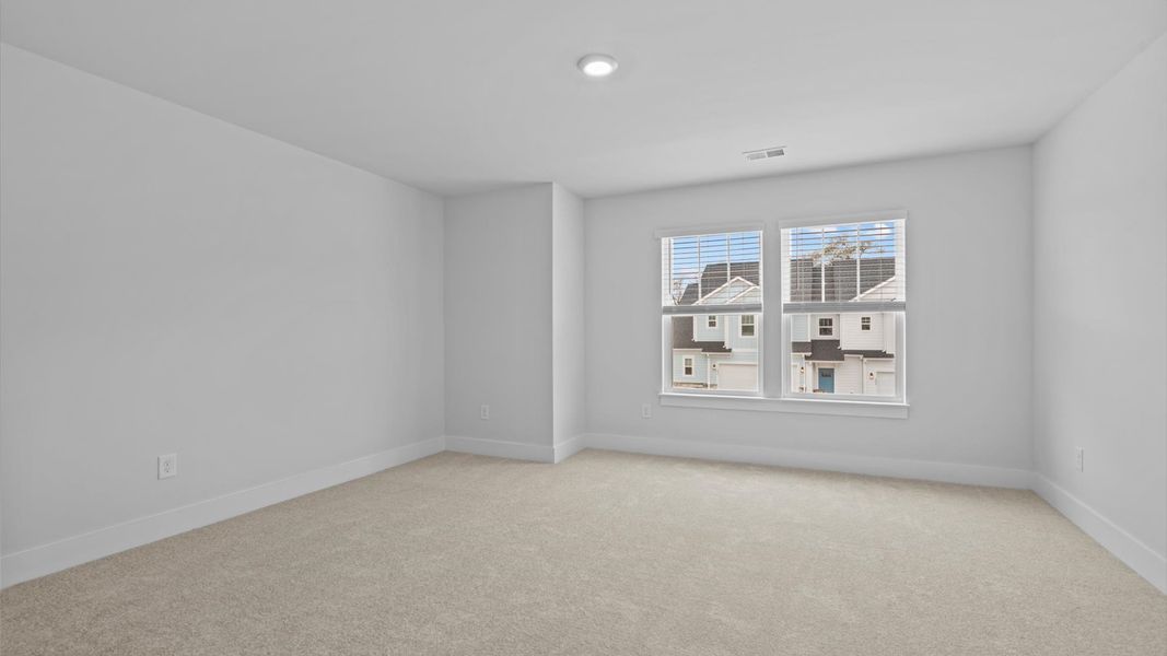 Tasteful bedroom with plush carpet, a walk-in closet, and large windows for abundant natural light