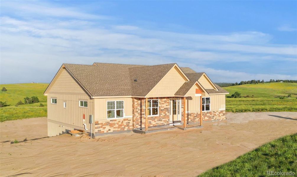 Front-facing view of the home in framing stage, illustrating rooflines and covered front entry.