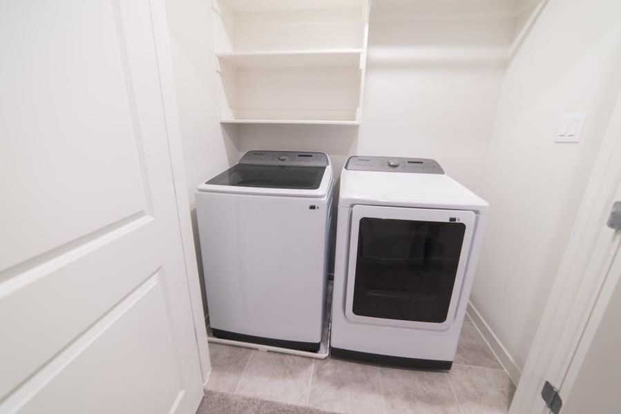Washroom featuring washing machine and dryer and light tile patterned flooring