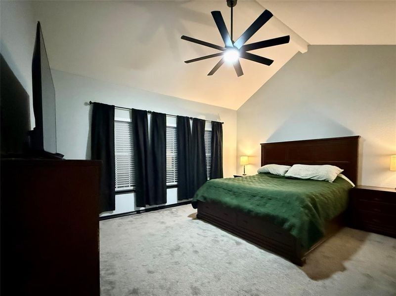 Primary bedroom with vaulted ceiling and windows looking into the back yard