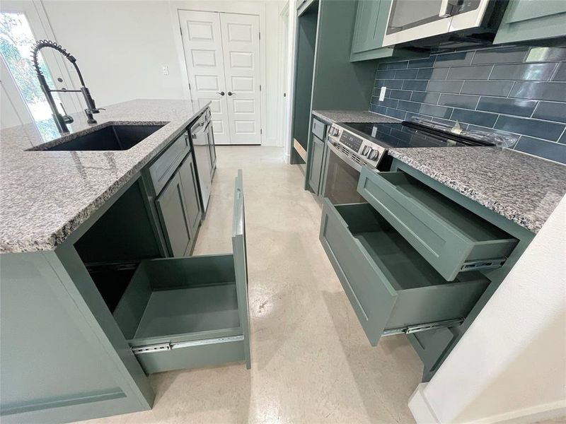 Kitchen with green cabinetry, sink, tasteful backsplash, stainless steel dishwasher, and light stone countertops