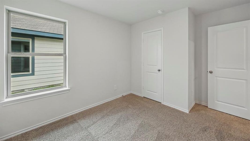 This room features neutral-toned carpet, white walls, and a window providing natural light