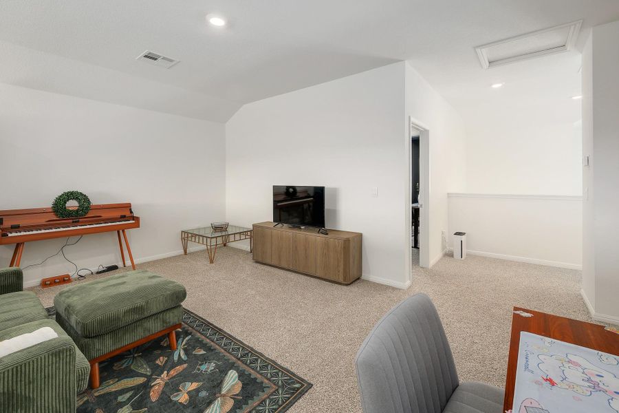 Carpeted interior space with a vaulted ceiling, recessed lighting, and a neutral wall palette Carpeted interior space with a vaulted ceiling, recessed lighting, and a neutral wall palette