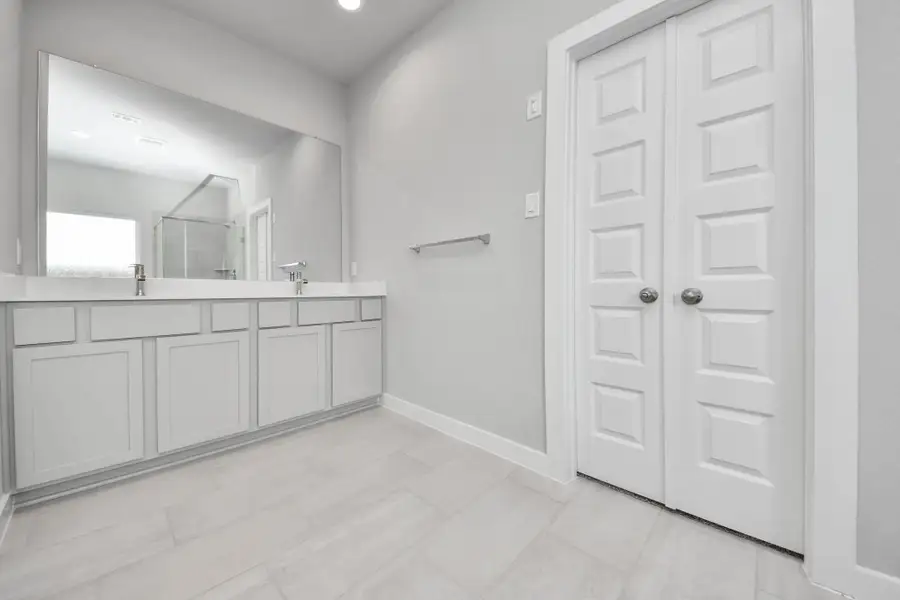 Elevate your daily routine at the elegant vanity, now equipped with double sinks, light countertops, modern hardware, and beautiful recessed lights. Sample photo of completed home with similar floor plan. Actual colors and selections may vary.