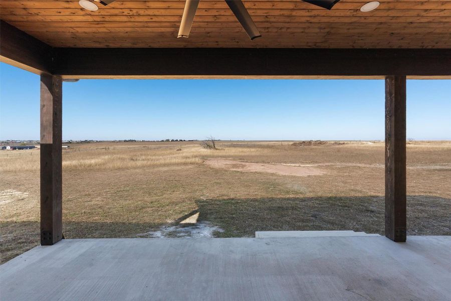 View of green lawn with a view of countryside, a ceiling fan, and a patio