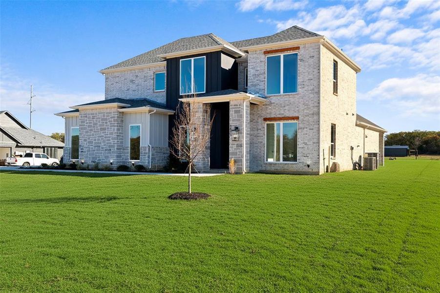 View of front of property with a front yard, board and batten siding, and brick siding View of front of property with a front yard, board and batten siding, and brick siding
