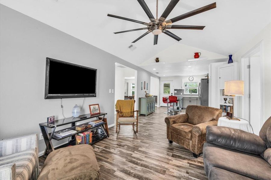 Living room with wood finished floors, vaulted ceiling, and ceiling fan
