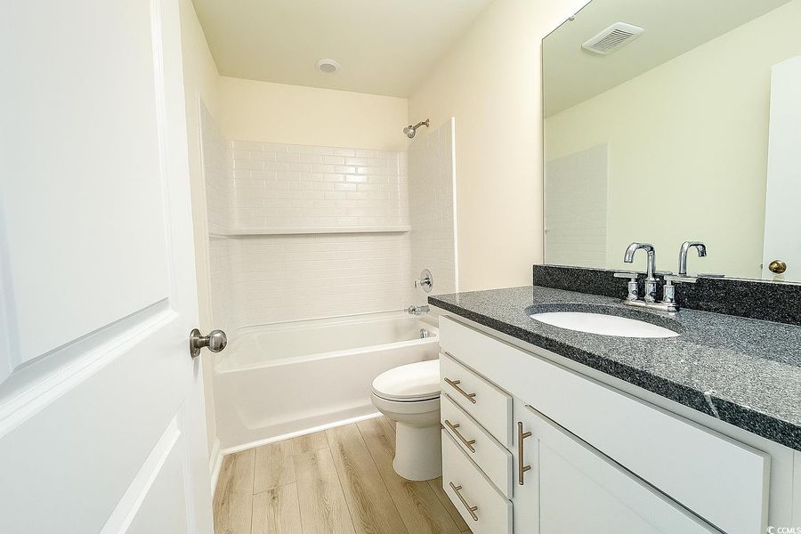 Full bath featuring vanity, wood finished floors, and tub / shower combination Full bath featuring vanity, wood finished floors, and tub / shower combination
