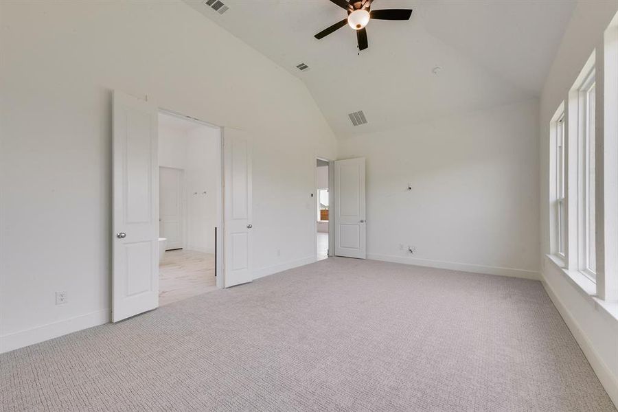 Unfurnished bedroom with light carpet, ceiling fan, and high vaulted ceiling Unfurnished bedroom with light carpet, ceiling fan, and high vaulted ceiling
