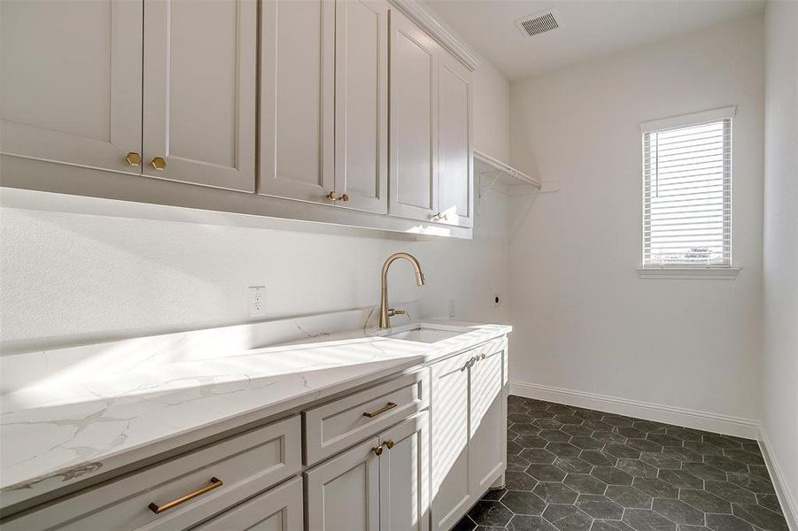 Utility room featuring built-in cabinets, tile floors, w/d hookup, and sink.