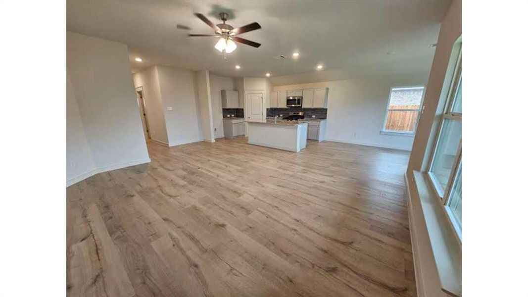 Open-concept living space featuring wood-finish flooring, recessed lighting, and a ceiling fan